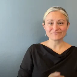 A screenshot of a white woman with blonde hair, from the Bridges Oregon organization, using ASL to sign a press release.