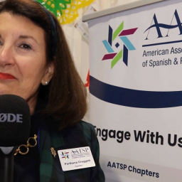 Woman with shoulder-length dark hair speaking in front of an AATSP banner.
