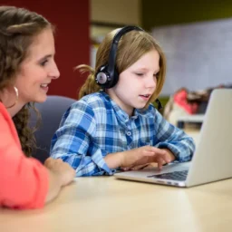teacher helping student take online language test.